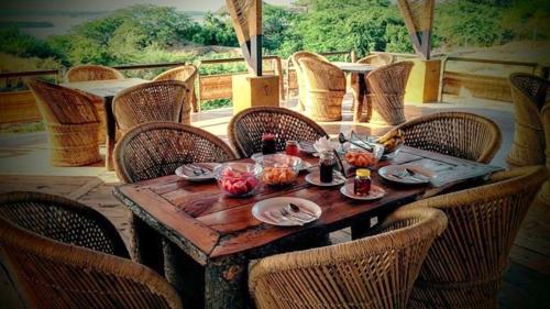 een houten tafel met stoelen eromheen met eten erop bij La Kamp Resort in Bhuj