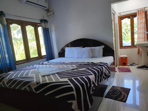 a bedroom with a bed with a black and white comforter at Hotel Highness Sea Rock in Neil Island