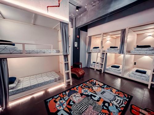 a room with three bunk beds and a rug at Bed Attitude Hostel Cenang in Pantai Cenang