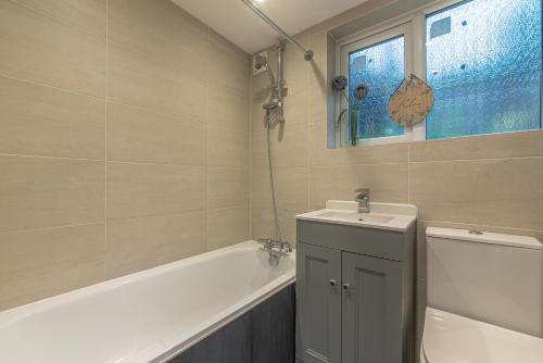 a bathroom with a tub and a sink and a toilet at Woodside House - 4 Bed Town House - Central Reading - Free Parking in Reading