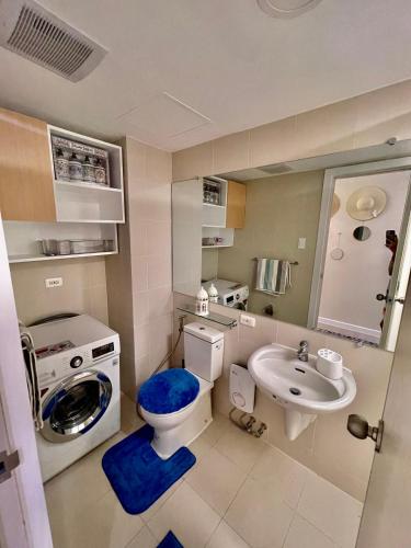 uma casa de banho com uma máquina de lavar roupa, um WC e um lavatório. em 2BR Bali IG Worthy Unit at Azure North San Fernando Pampanga em San Fernando