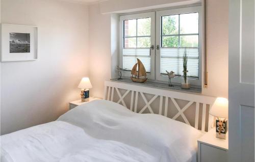 ein weißes Schlafzimmer mit einem Bett und einem Fenster in der Unterkunft Strandhafer in Gollwitz