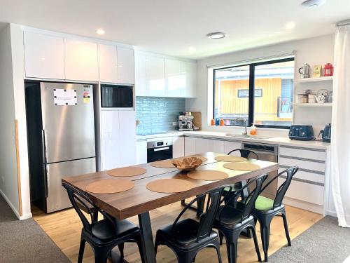 a kitchen with a wooden table with chairs and a refrigerator at MyHolidays - The Four Seasons Queenstown in Queenstown