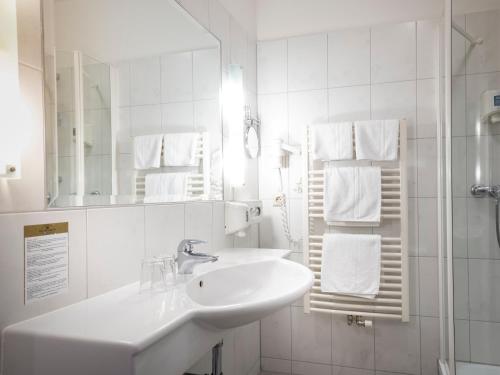 a white bathroom with a sink and a mirror at Hotel Moarhof in Lienz