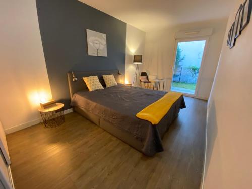 um quarto com uma cama e uma grande janela em Le Parc em Bergerac