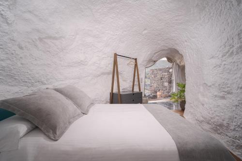 1 dormitorio con 1 cama en una pared de piedra en Redondo de Guayedra, en Guayedra