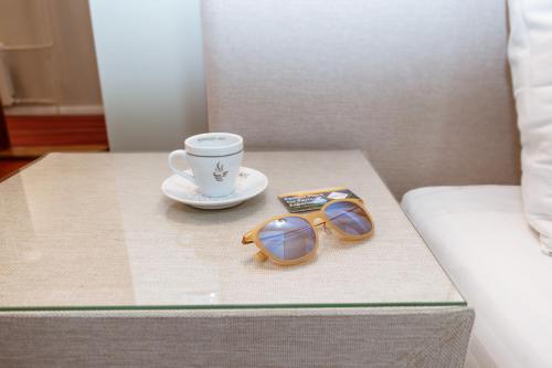 a pair of glasses and a cup of coffee on a table at Zepter Hotel Vrnjacka Banja, member of Zepter Hotels in Vrnjačka Banja