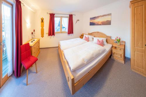 een slaapkamer met een groot bed en een rode stoel bij Ferienwohnungen Arnspitz in Krün