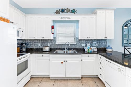 a white kitchen with white cabinets and a sink at Turtle's Nest West in Gulf Shores