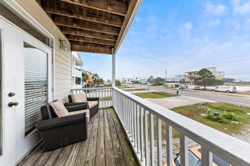 a balcony with two chairs and a view of a street at Turtle's Nest West in Gulf Shores