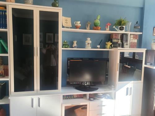 un centro de entretenimiento blanco con televisión. en Apartamentos Clotilde con Wifi incluido - Candás, en Candás