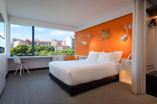 um quarto de hotel com uma cama e uma grande janela em EVOLUTION Lisboa Hotel em Lisboa