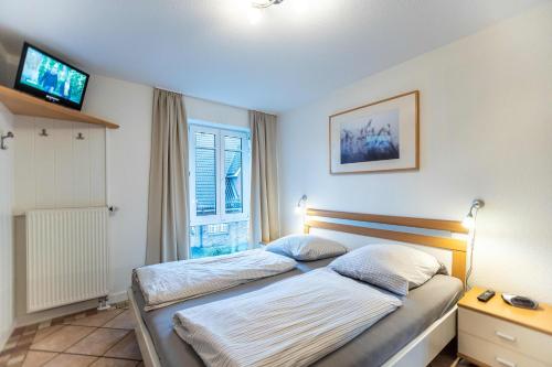 een slaapkamer met 2 bedden, een tv en een raam bij Hüs Martens in Wyk auf Föhr