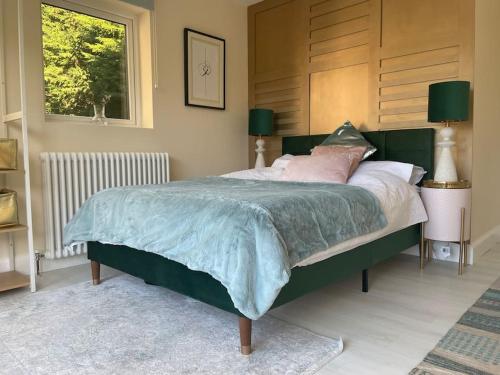 Un dormitorio con una gran cama verde con almohadas rosas en Edge Water Cottage-recently constructed, en Crawfordsburn