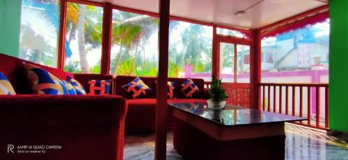 a living room with a red couch and a table at Hotel Highness Sea Rock in Neil Island