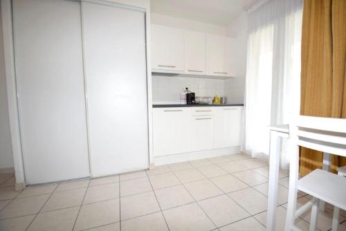 Il comprend une cuisine avec des placards blancs et du carrelage blanc. dans l'établissement Palais des Domes Piscine et Parking, à Nice