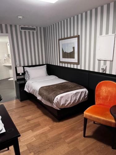 a bedroom with a bed and a chair and a table at Logis Hôtel Ettenheim in Strasbourg