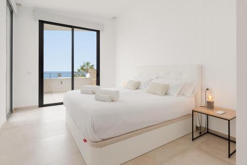 a white bedroom with a large white bed and a window at Karat Villa Neveda in Adeje