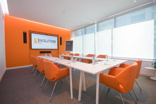 a conference room with a long table and orange chairs at EVOLUTION Lisboa Hotel in Lisbon
