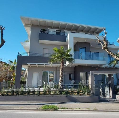a white building with a palm tree in front of it at Appartamento Garden in Riccione