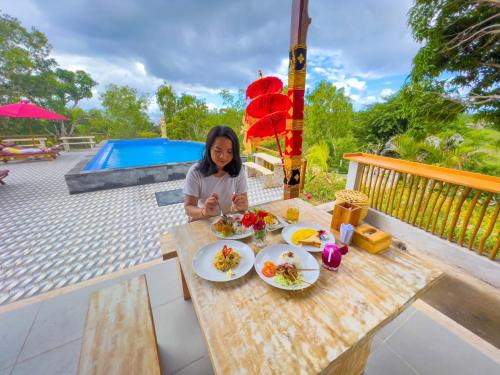 een vrouw aan een tafel met borden eten bij Innora Jungle Resort And Spa in Nusa Penida