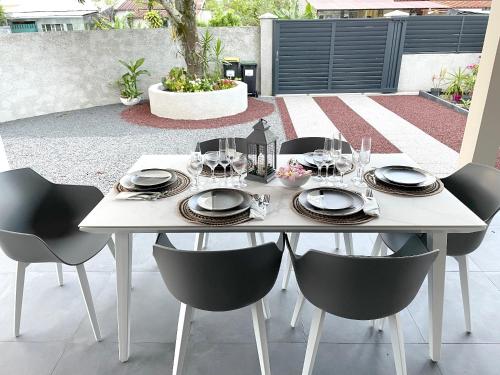 einen weißen Tisch mit Stühlen, Tellern und Weingläsern in der Unterkunft Villa de 3 chambres avec jardin clos et wifi a Bras Panon in Bras-Panon
