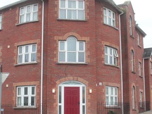 un edificio de ladrillo rojo con puerta roja en The Otton Suite, en Dungannon