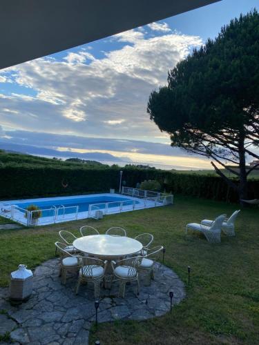 a table and chairs in a yard with a pool at El Tejado de Santa Ana in Barrika