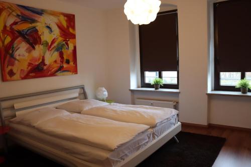 uma cama num quarto com duas janelas e um quadro em alexxanders Apartments & Studios em Chemnitz