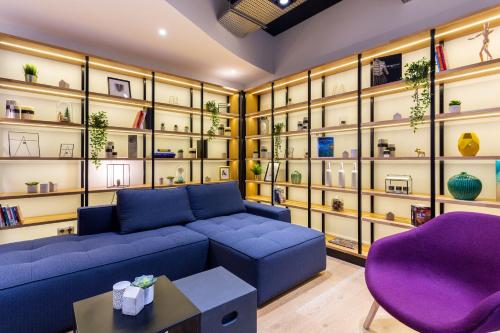 - un salon avec un canapé bleu et un fauteuil violet dans l'établissement Campanile Laval Nord, à Changé