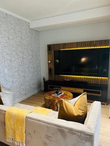 a living room with a white couch and a large television at Ellipse Apartment in Midrand