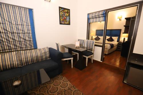 sala de estar con sofá, mesa y cama en Hotel Capitol Hills - Greater Kailash Delhi en Nueva Delhi