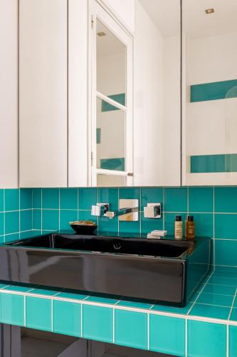 une salle de bain avec un lavabo et un miroir dans l'établissement Veeve - Impressions of the Eiffel Tower, à Paris