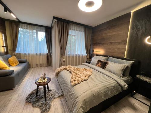 a bedroom with a large bed and a couch at Апартамент - Боровец Хотел ''Боровец Гардънс'' A 44 in Borovets