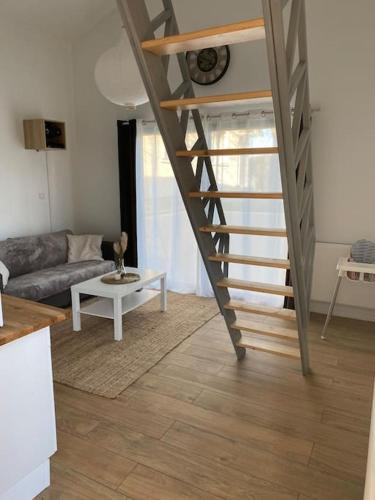 a staircase in a living room with a couch and a table at Logement avec mezzanine in Tremblay En France