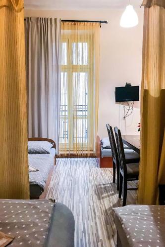 a room with two beds and a table and a window at Apartaments Piotrkowska 101 in Łódź