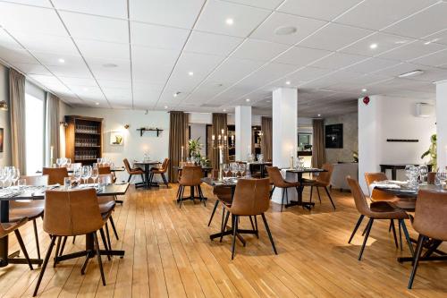 un restaurante con suelo de madera, mesas y sillas en Best Western Plus Edward Hotel en Lidköping