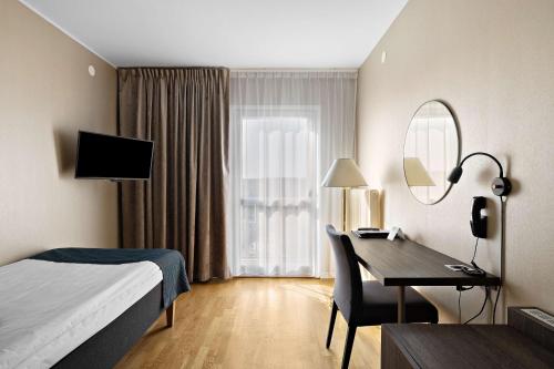 a hotel room with a bed and a desk and a mirror at Best Western Motala Stadshotell in Motala