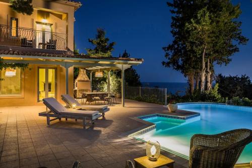 een achtertuin met een zwembad en een huis bij Unique Kefalonia Ionian Sands Villa in Lourdhata