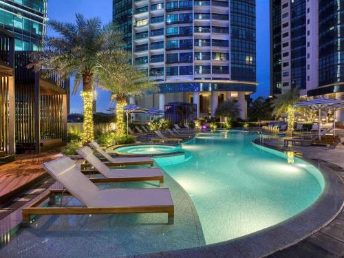 a swimming pool with lounge chairs and a building at Sofitel Kuala Lumpur Damansara in Kuala Lumpur