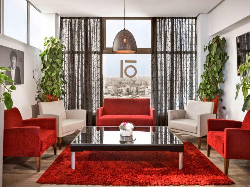 a living room with red chairs and a table at Mövenpick Hotel Casablanca in Casablanca