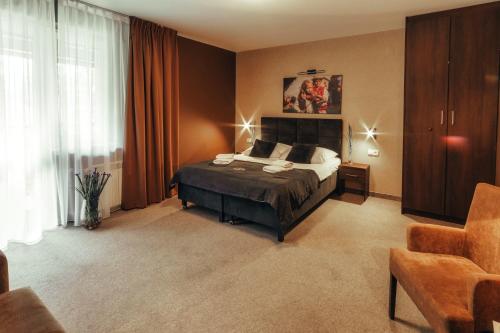 a bedroom with a bed and a chair in it at Srebrny Bucznik Wellness & Restaurant in Istebna