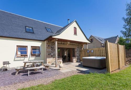 a backyard with a bench and a hot tub at Laurel Cottage at Williamscraig Holiday Cottages in Linlithgow