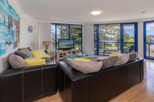 a living room with two leather couches and a television at Heritage 302 in Tuncurry