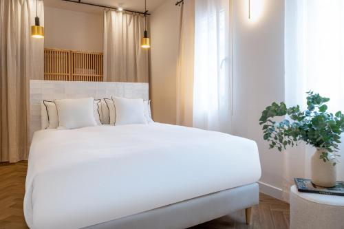 Cama blanca grande en habitación con planta en Magno Apartments Robles with Bath Tub and Private Parking en Sevilla