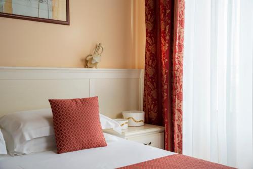 een slaapkamer met een bed met een rood kussen en een raam bij Hotel Mayer & Splendid - Wellness e Spa in Desenzano del Garda