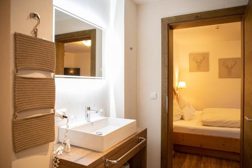 a bathroom with a sink and a mirror and a bed at Appartements Kirchenwirt in Kirchberg in Tirol