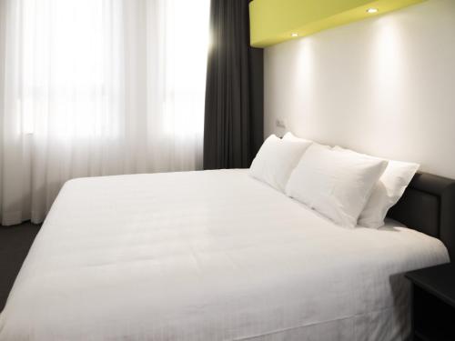sypialnia z białym łóżkiem i białymi poduszkami w obiekcie Loto Business Hotel w Rzymie