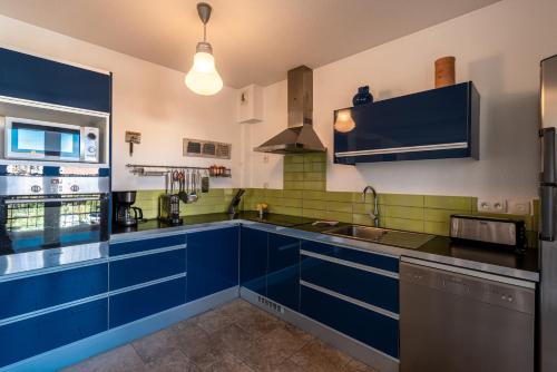 a kitchen with blue cabinets and a sink at Isula Rossa in LʼÎle-Rousse