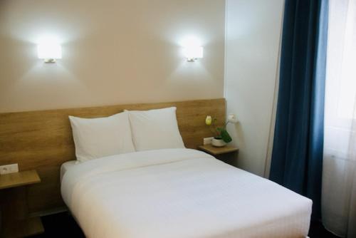 a bedroom with a bed with white sheets and two lights at Appart' hôtel 7 sensation in Bougival